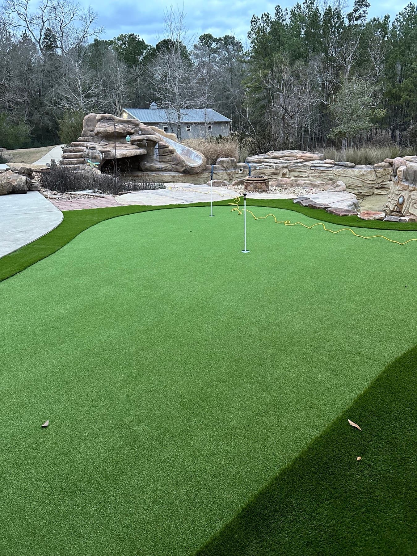 Backyard artificial-turf putting green with a rock water feature