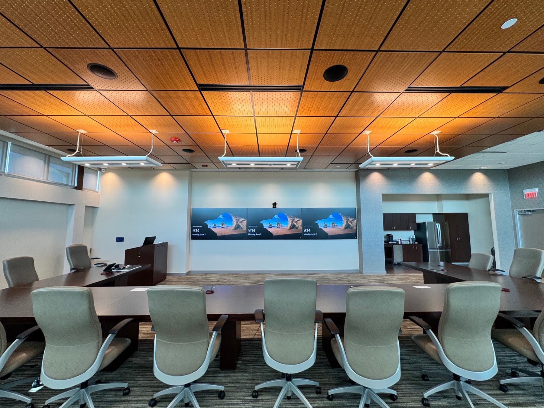 Corporate boardroom with a three-panel video conferencing wall and pendant lighting