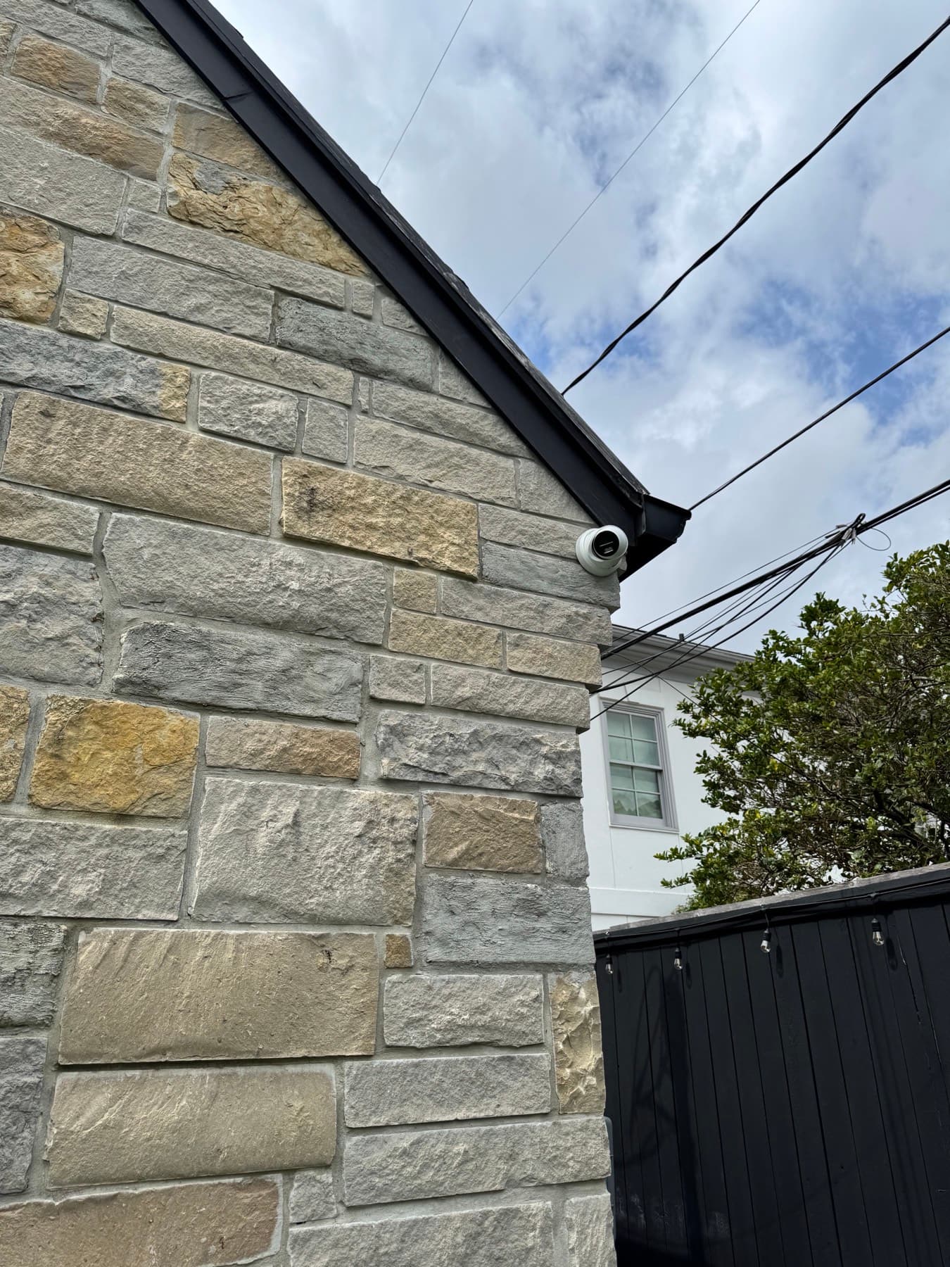 Dome surveillance camera mounted under the eave of a stone home