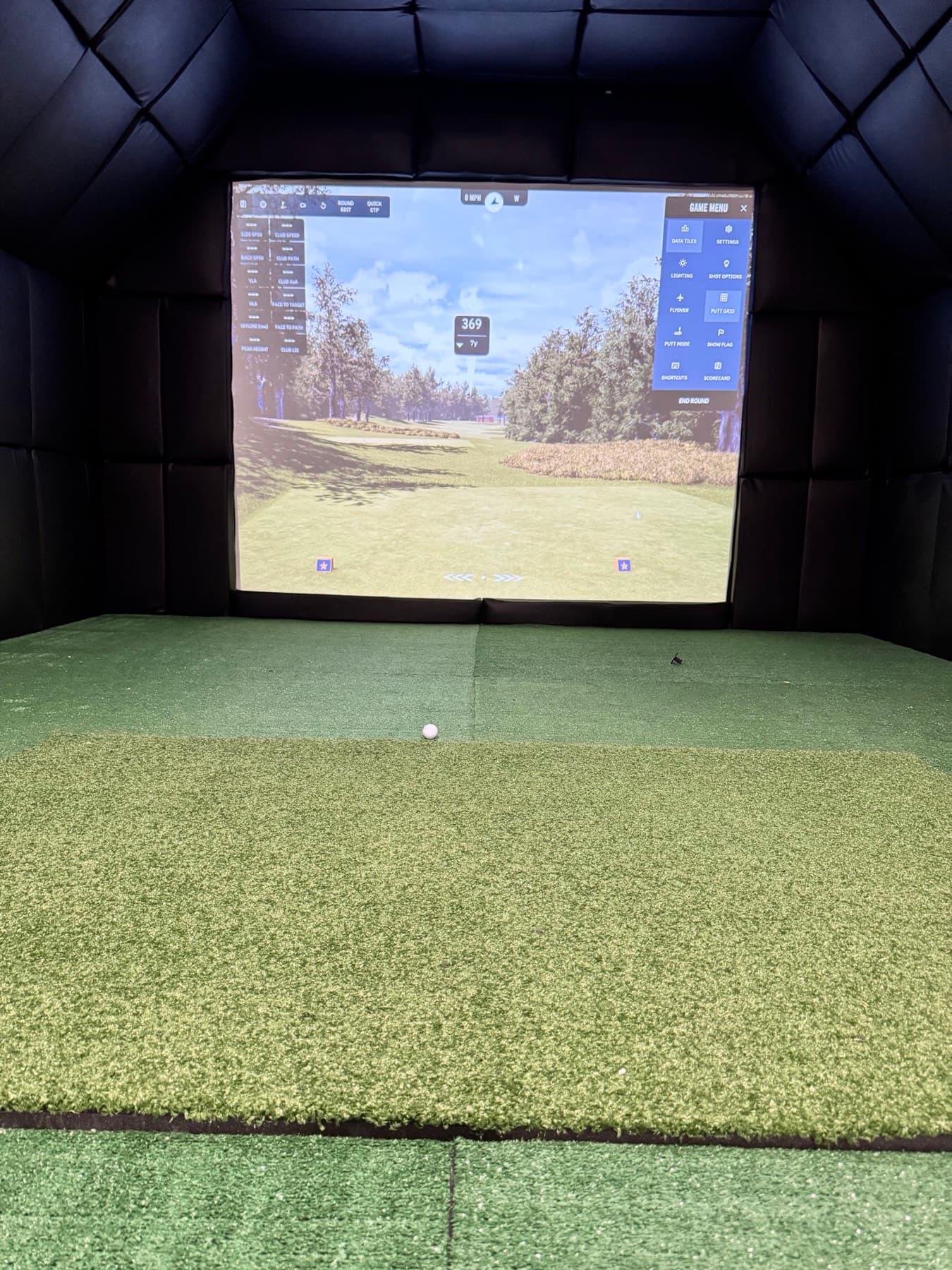 Golf simulator hitting bay with a course projected on the impact screen