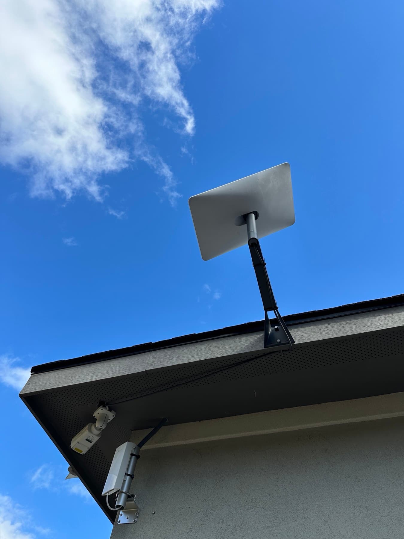Starlink satellite dish mounted on a roofline against a blue sky